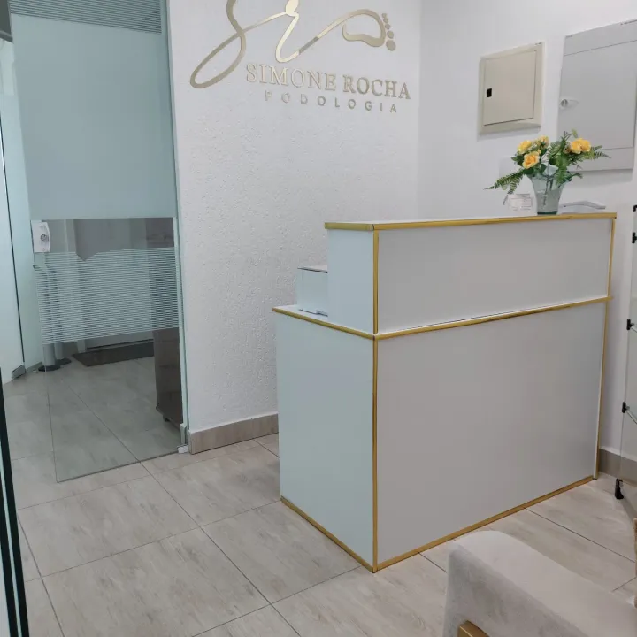 Recepção da clínica com a marca Podologia Simone Rocha na parede